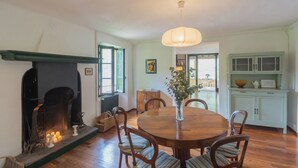 A dining room with a fireplace, wooden table, chairs, and a hanging light fixture. - Residenza Regina by Rent all Como (Laglio)
