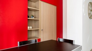 A conference room with a dark wooden table, red walls, and a wooden cabinet with shelves.