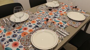 Et spisebord dækket med tallerkener, glas og bestik, med en borddug med et mønster.