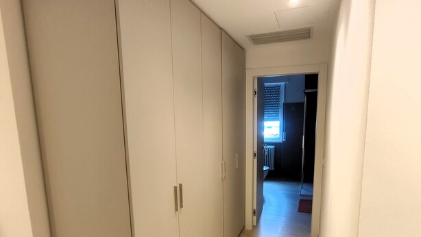 En gang med et garderobeskab, en radiator og en dør til et andet rum.
