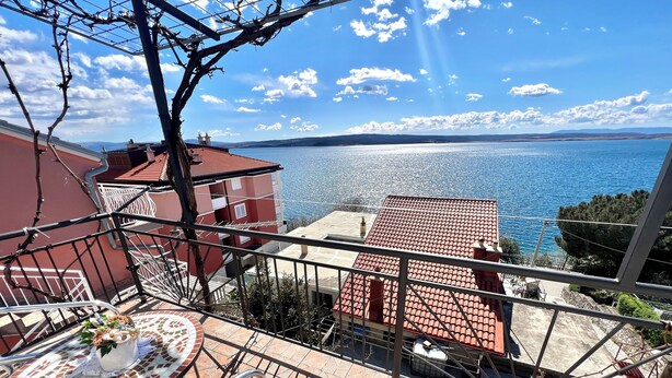 A balcony with a view of the sea, a tiled table, and a cushioned chair. - Studio Apartman Mare 2 (Dramalj)