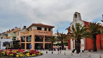 Un edificio con el letrero 'Maison des Artes', una calle con separadores de tráfico y una jardinera.