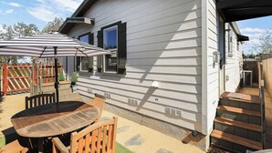 Een huis met een patio, compleet met een tafel, stoelen, een houten omheining en een overdekte zithoek.