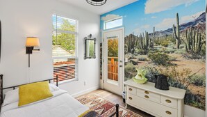 A bedroom with a bed, a nightstand, a dresser, a window with blinds, and a mural of a desert landscape. - Disney SoFi Stadium Hollywood Beaches Close! Central AC (Norwalk)