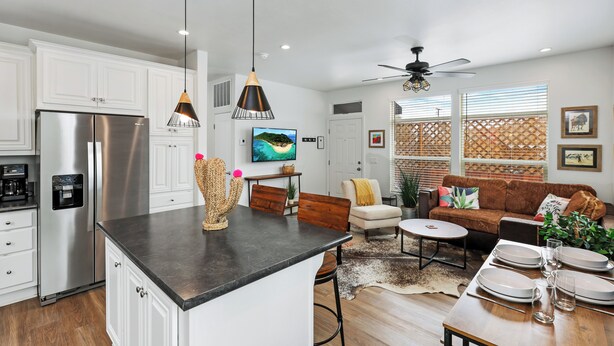 A modern kitchen with white cabinets, a stainless steel refrigerator, and a dining area with a brown sofa and a coffee table. - Disney SoFi Stadium Hollywood Beaches Close! Central AC (Norwalk)