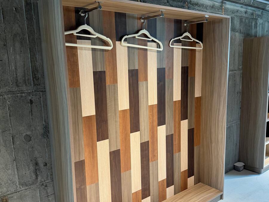 A wardrobe with a geometric wood pattern and three white hangers.