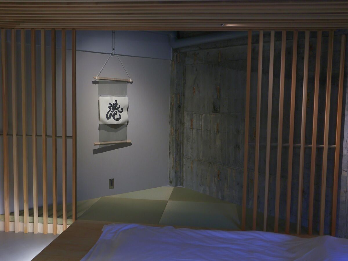 A minimalist room with a bed, a wall-mounted shelf, and a sliding door.