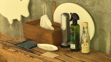 Una encimera de madera con una caja de pañuelos, un pulverizador, una botella de vidrio y un plato.