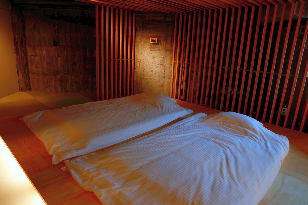 Une pièce avec un mur lambrissé en bois, un lit avec une literie blanche et une petite fenêtre.