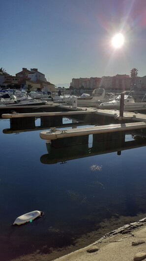 Una marina con barche ormeggiate, acqua calma e edifici sullo sfondo.