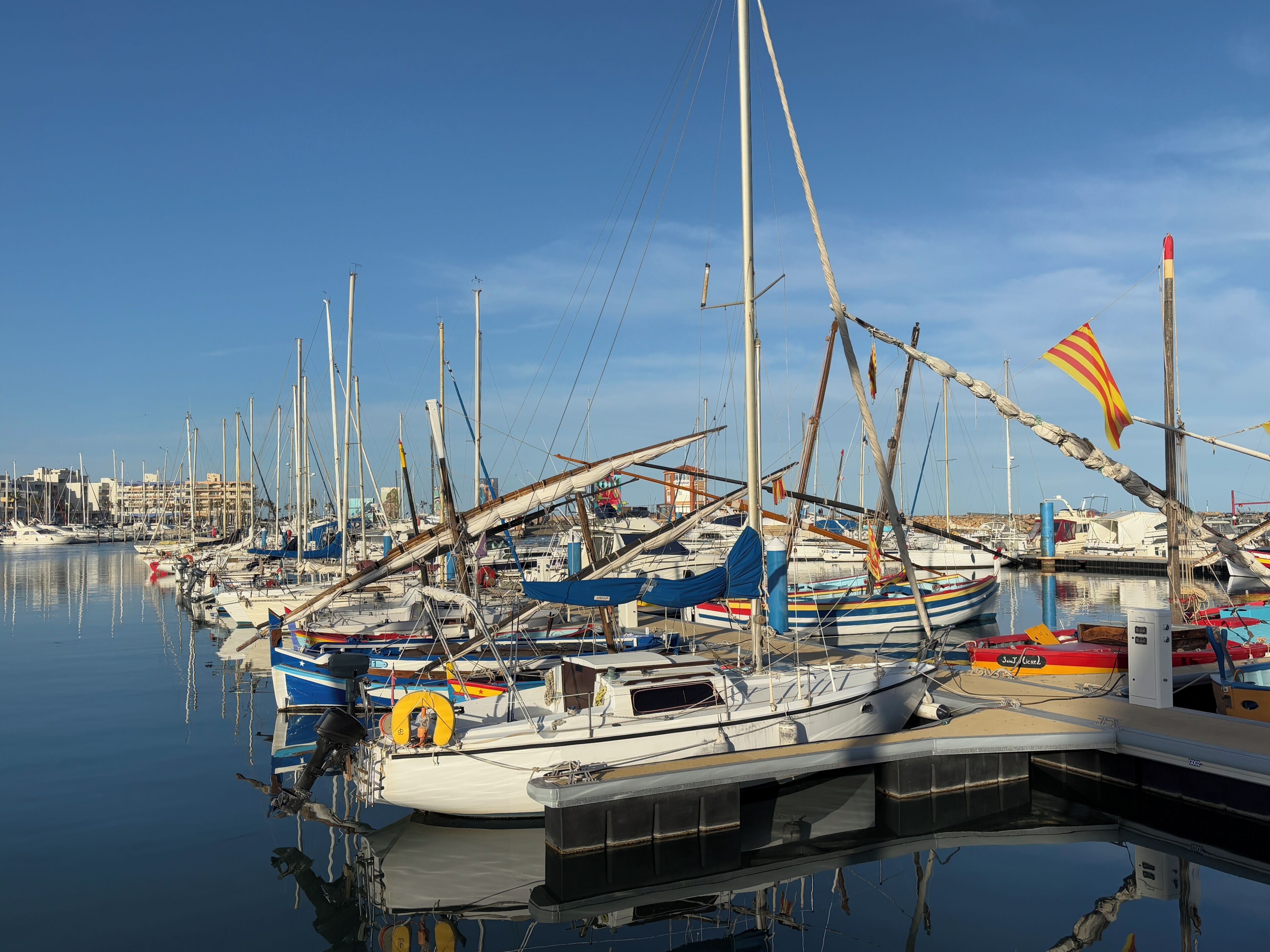 Een jachthaven met meerdere boten aanmeren, kalm water en een heldere lucht.