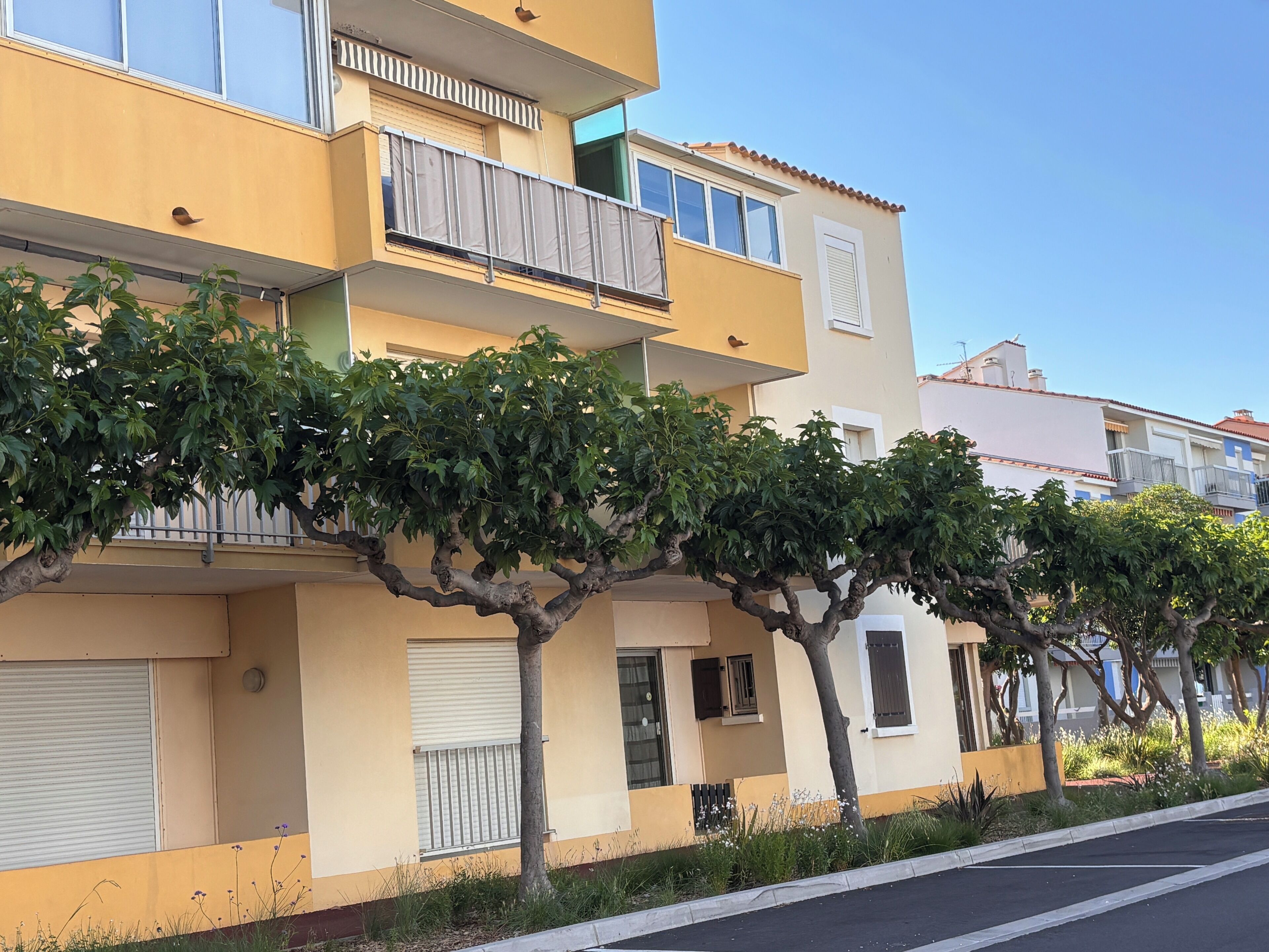Un edificio residencial de varios pisos con balcones, techo plano y cielo despejado.