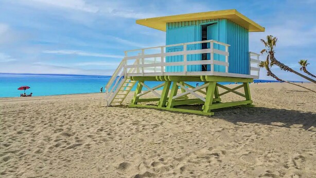 Une tour de surveillance sur une plage, avec un ciel dégagé et une vue sur l’océan.