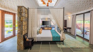 Ein geräumiges Schlafzimmer mit Steinwand, einem großen Bett, einem Fernseher und Blick ins Freie.