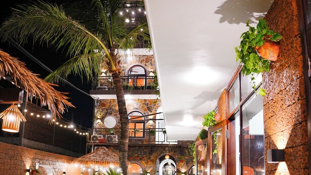 A pool area with a tiled edge, potted plants, and a palm tree. - Serena Tam Coc Hotel & Villa (Nam Hoa Lu)