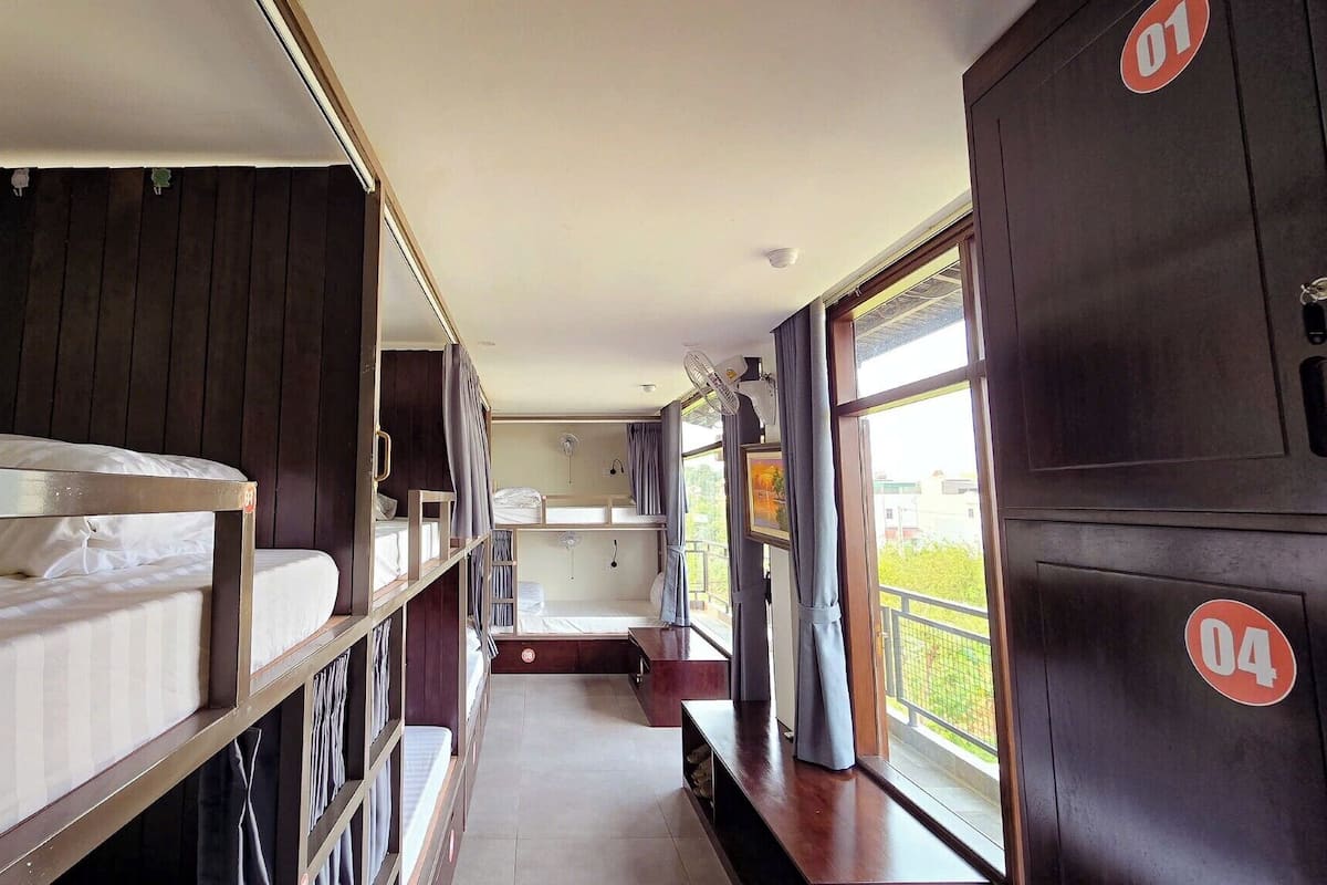 A train carriage with bunk beds, a small kitchenette, and large windows offering views of the outside.