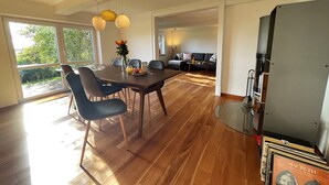 Amplia sala de estar con mesa de comedor, sillas y sofá. Una ventana grande ofrece luz natural y vistas al exterior.