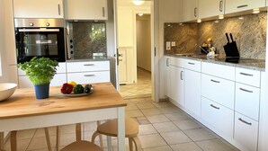 Una cocina moderna con armarios blancos, encimera de granito y una mesa de comedor de madera con sillas.