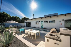 Un patio al aire libre con mesa de billar, asientos y zona de barbacoa.