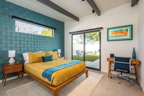 Un dormitorio con cama, mesitas de noche, escritorio y silla.