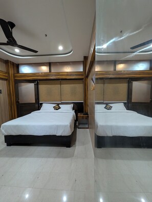 Quarto de hotel moderno com duas camas, um ventilador de teto e um espelho grande.