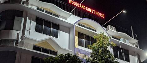 A multi-story building with a sign reading "WOODLAND GUEST HOUSE".
