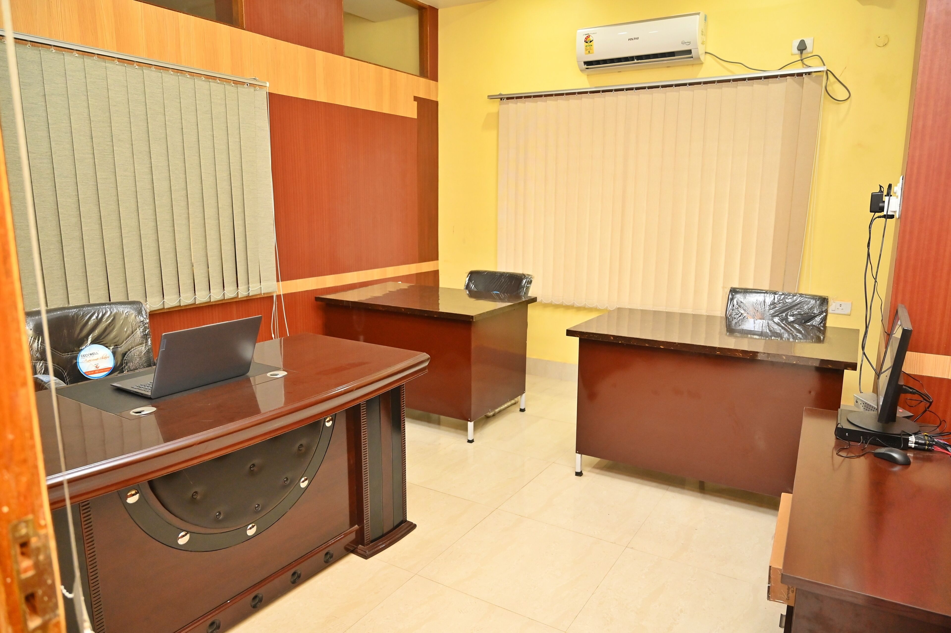 A reception area with a wooden desk, a laptop, and a telephone.