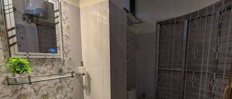 A bathroom with a pedestal sink, toilet, and shower area.