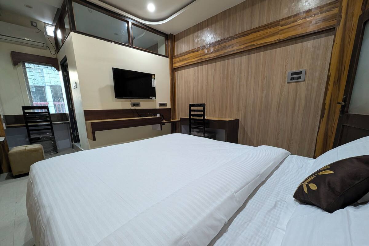 Een hotelkamer met een groot bed, een bureau, een stoel, een televisie en een wandpaneel van hout.