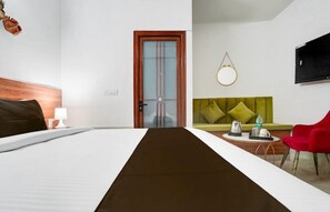 Una habitación de hotel con cama, escritorio, silla, televisor y puerta.