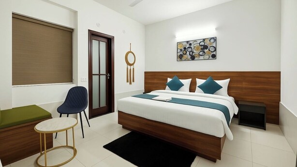Een moderne hotelkamer met een bed, een stoel, een klein tafeltje en een groene bank.