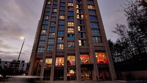 A tall hotel with multiple floors, large windows, and a prominent entrance with illuminated signage. - Student only Premium Studio at Lewisham Exchange (London)