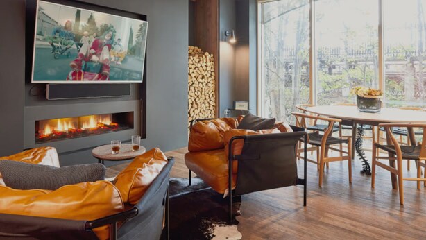 A modern living room with a fireplace, leather sofa, and a dining area with a table and chairs. - Student only Premium Studio at Lewisham Exchange (London)