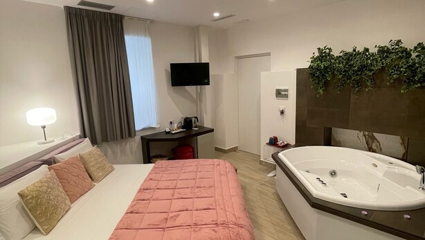 Ein modernes Hotelzimmer mit Bett, Schreibtisch, Fernseher und einem Badezimmer mit Badewanne.