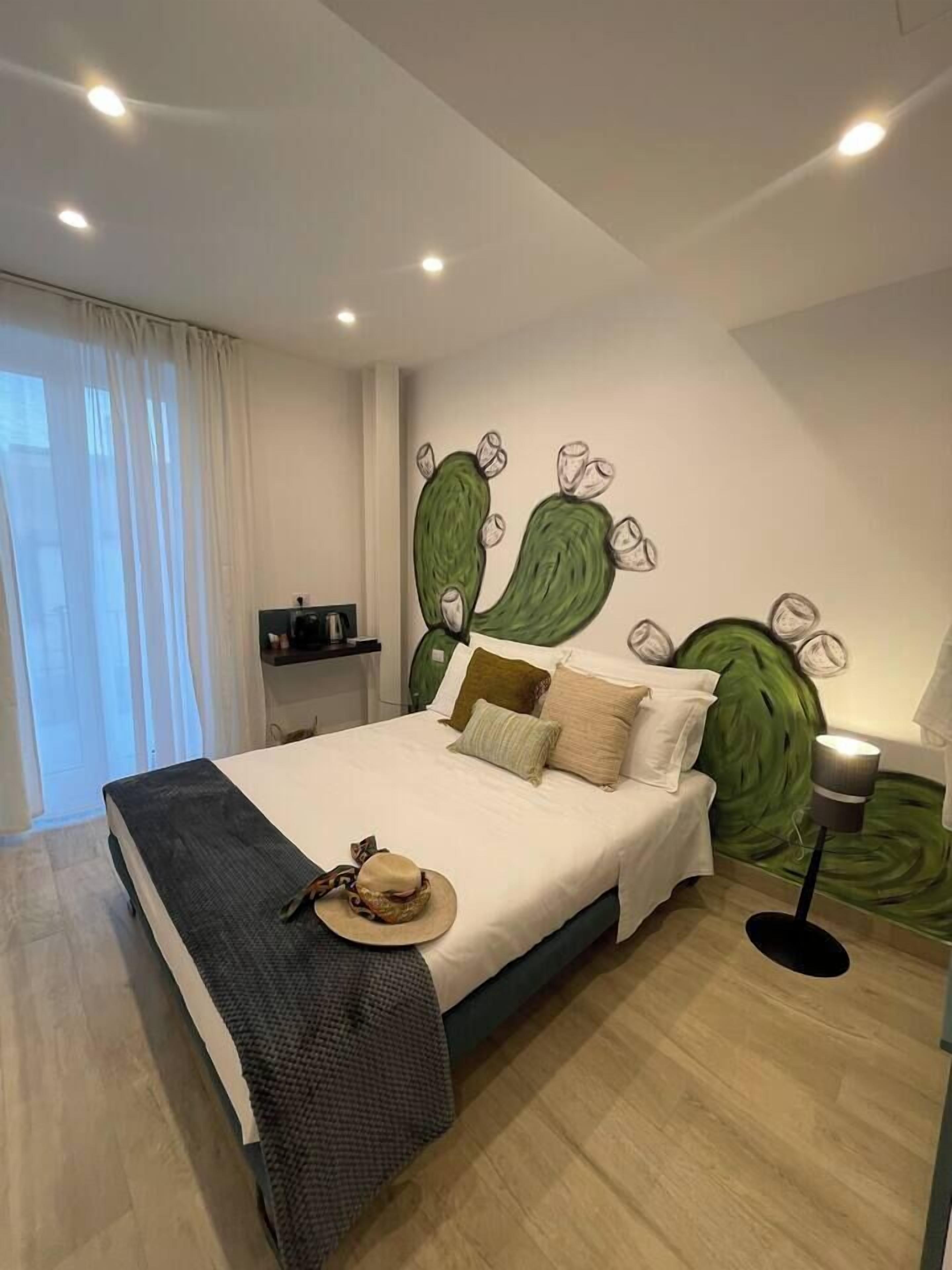 Ein Schlafzimmer mit einem Bett, Kissen, einem Hut und einer Wandmalerei.