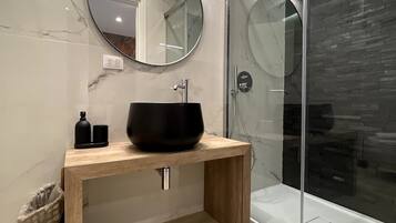 A modern bathroom with a wooden vanity, a black vessel sink, and a glass shower enclosure.