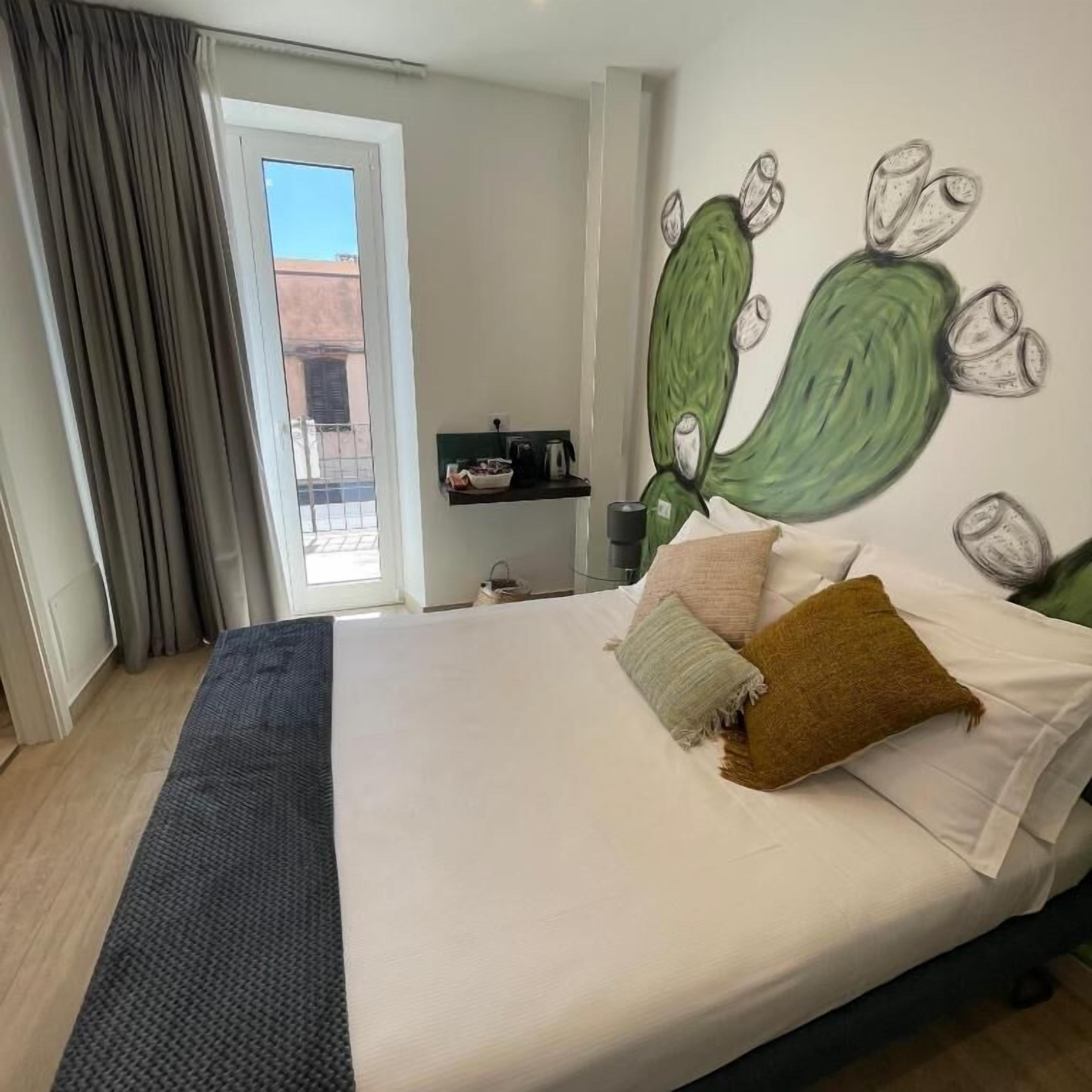 Une chambre à coucher avec un lit, des oreillers, une table de chevet, une machine à café et une vue sur l’extérieur.