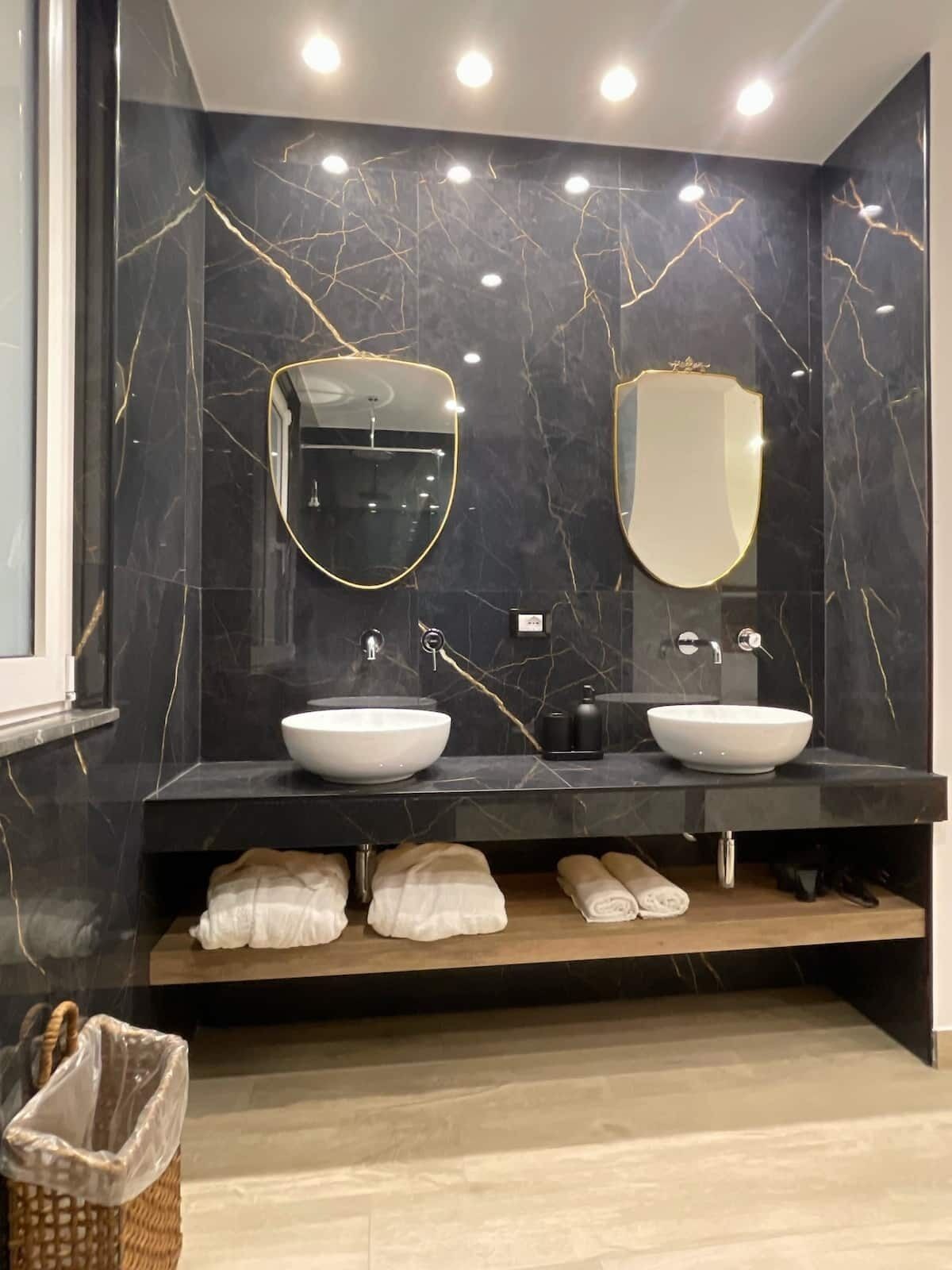 Ein modernes Badezimmer mit zwei Waschbecken, Marmorwänden und einer Holzeinrichtung.