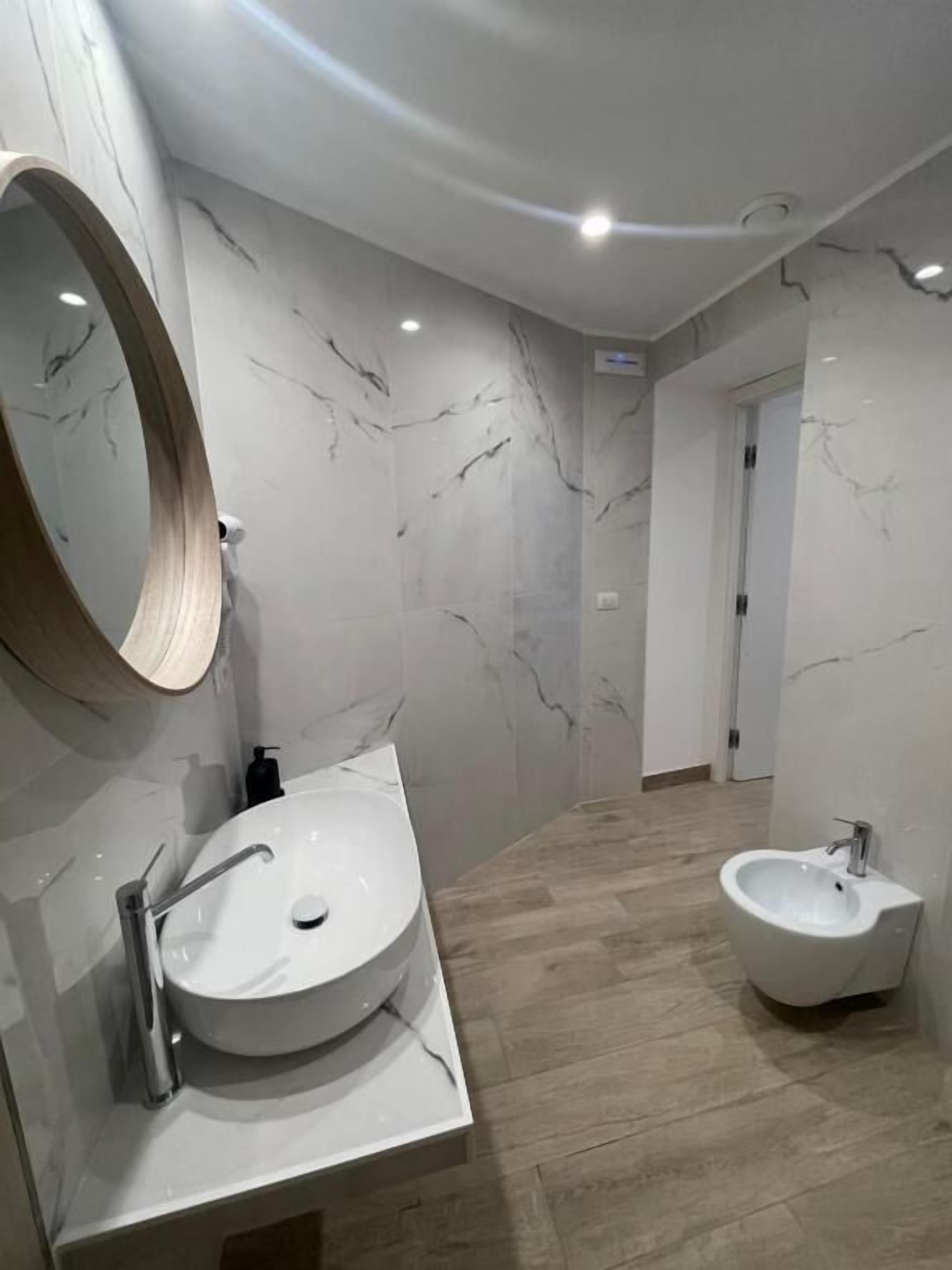 Une salle de bain moderne avec un grand lavabo ovale, un miroir rond et un meuble-lavabo sur pied.