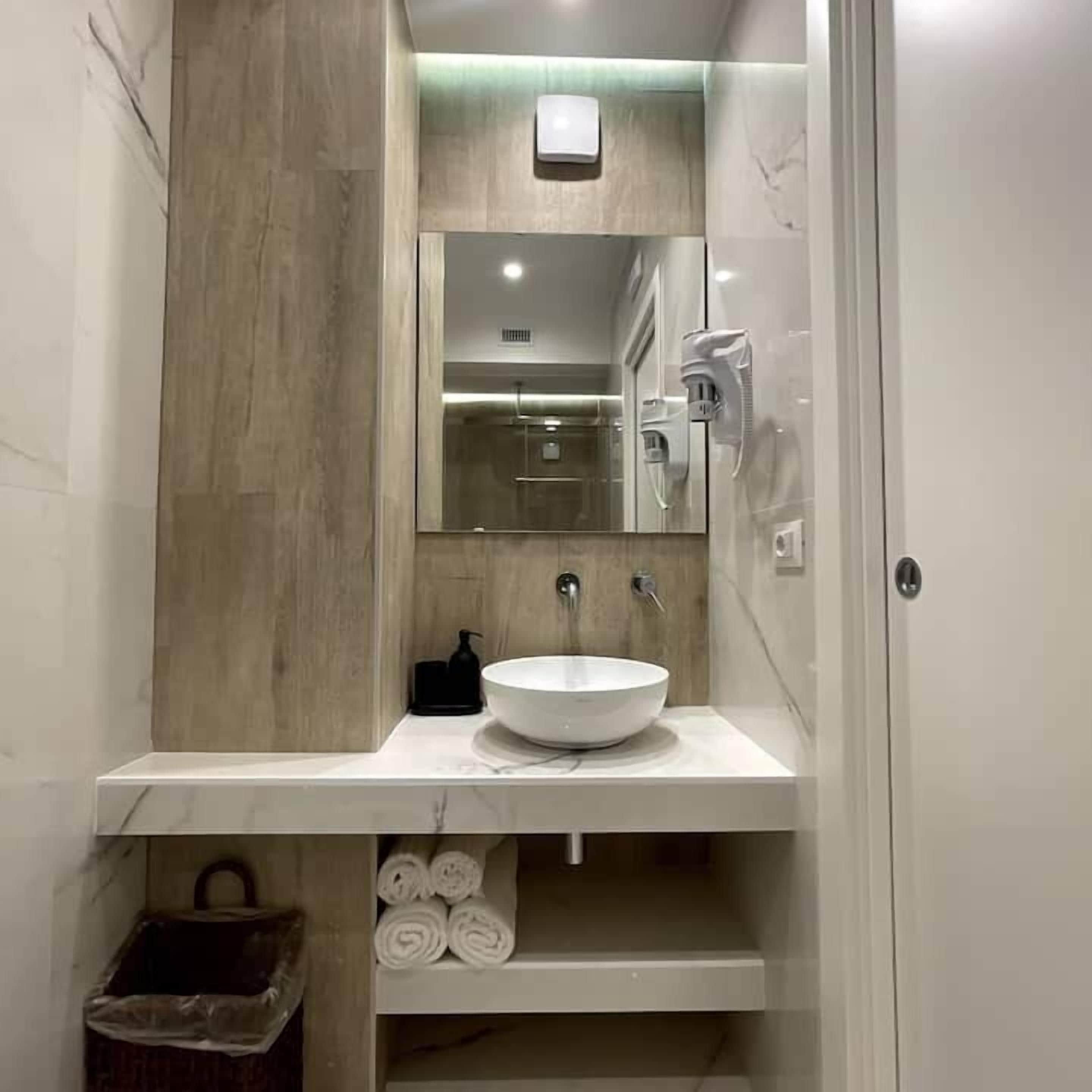 A modern bathroom with a marble vanity, a large mirror, a wall-mounted heater, and a towel rack.