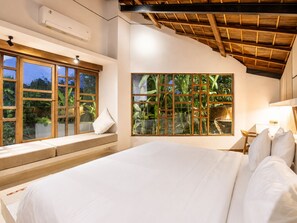 A bedroom with a large bed, a window with a view of greenery, and a ceiling with exposed wooden beams. - Chic 2-BR Villa with Pool, 800m to Canggu Beach (Kecamatan Mengwi)