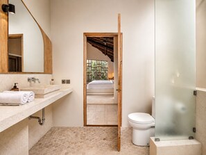 A bathroom with a wooden door leading to a bedroom, a toilet, and a mirror above the sink. - Chic 2-BR Villa with Pool, 800m to Canggu Beach (Kecamatan Mengwi)