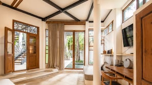A spacious room with a large window, a wooden desk, a television, and a staircase leading to an outdoor area. - Designer 2-BR Villa Pool, 800m to Canggu Beach (Kecamatan Mengwi)