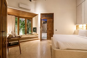 Une chambre à coucher comprenant un lit, une chaise, une fenêtre avec des rideaux et une porte donnant sur une autre pièce.