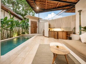 Un espace de vie extérieur moderne comprenant une piscine, une table en bois et un coin cuisine.