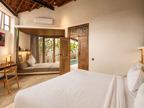 Un dormitorio con una cama, un escritorio y ventana con vistas a una zona de piscina.