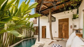 A poolside area with a built-in bench, a wooden door, and a white wall.