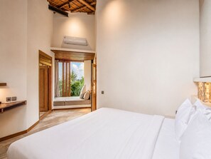 Une chambre à coucher avec un lit, une fenêtre avec des rideaux, une porte en bois et un ventilateur de plafond.