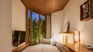 A bedroom with a bed, TV, wooden desk, and a view of greenery. - Opulent 1-BR Villa Just 800m from Canggu Beach (Kecamatan Mengwi)
