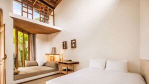 A bedroom with a bed, a desk, a chair, and a window overlooking greenery. - Opulent 1-BR Villa Just 800m from Canggu Beach (Kecamatan Mengwi)